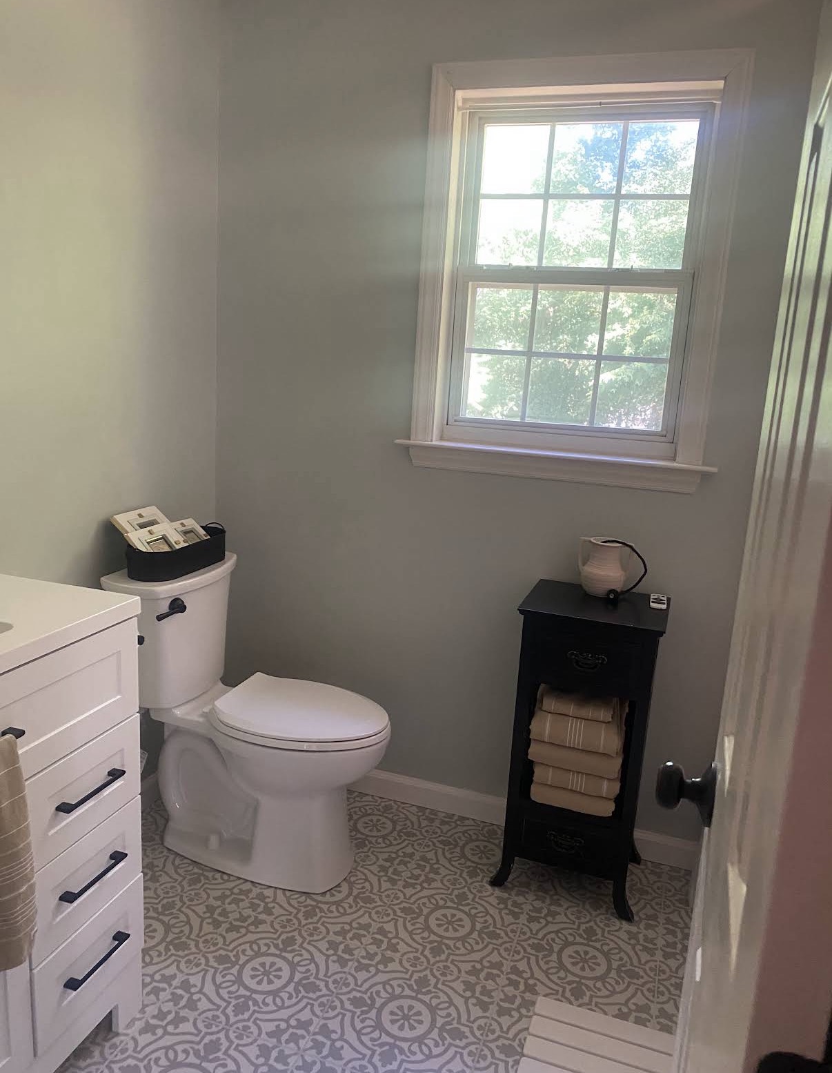 Finished bathroom with patterned flooring, white fixtures and freshly painted walls