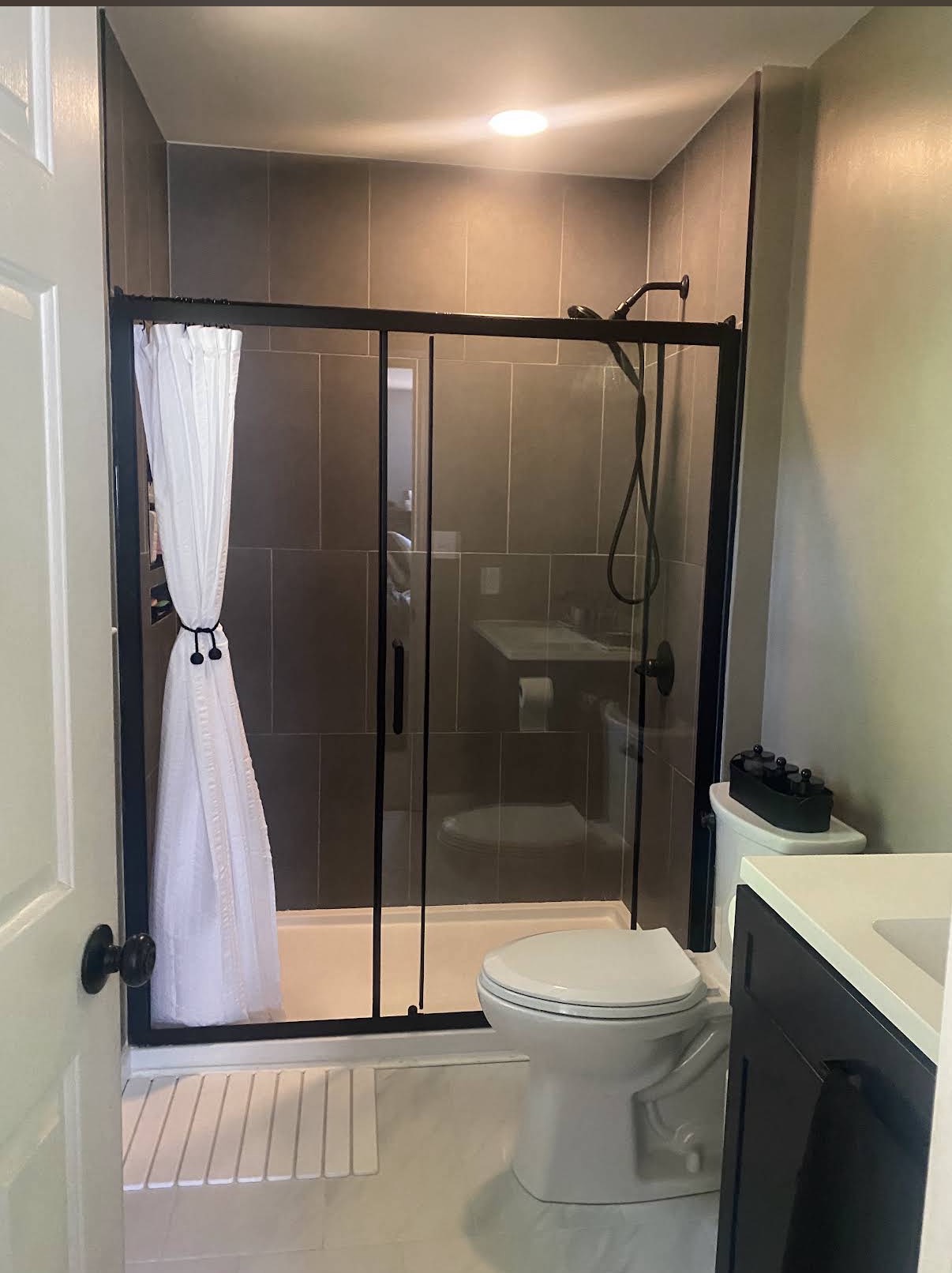 Finished tile shower with black-framed glass enclosure and black fixtures