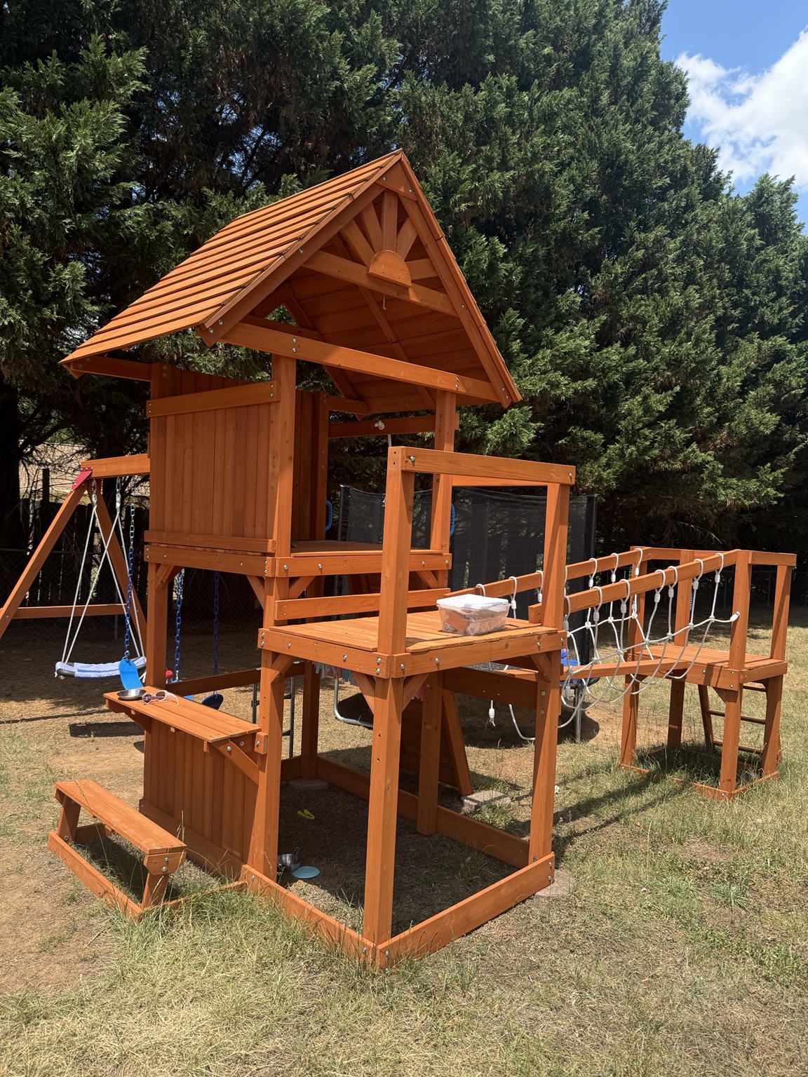 Custom-built wooden backyard playset with slide and climbing features