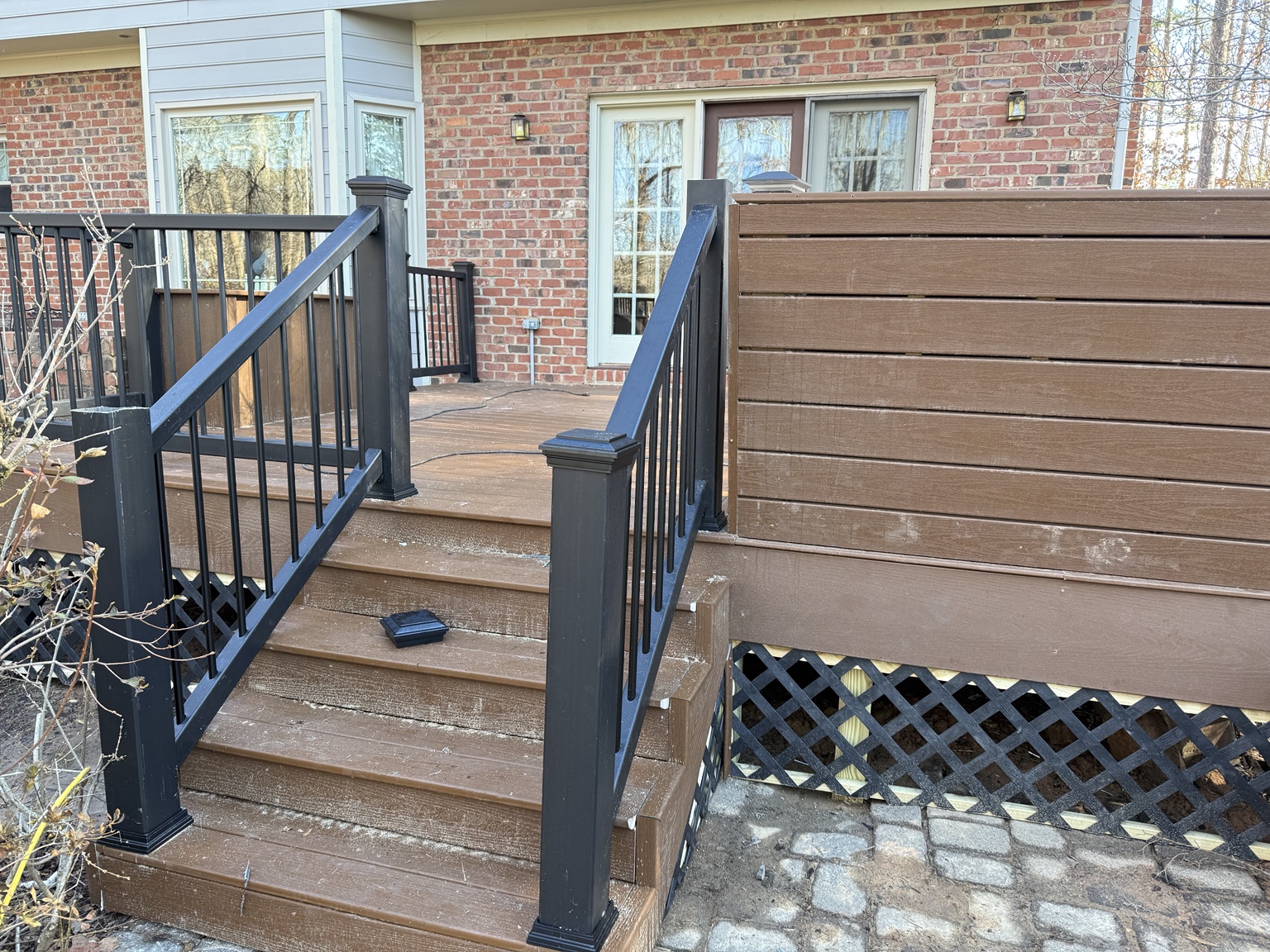 Composite deck stairs with black aluminum railing and privacy wall